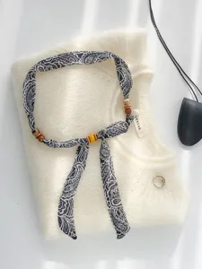Vintage Paisley Band Perlen Halskette Detail mit Holzperlen auf weissem feinem Strickpullover.