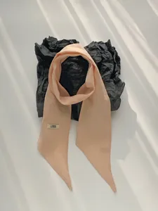 Linnen twilly sjaal detail, smalle hals lint, effen abrikoos kleur, minimalistisch design.