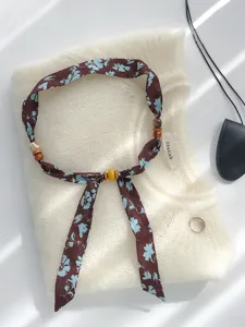 Detailaufnahme einer Retro Stoff Band Halskette mit blauen Blumen und Holzperlen.