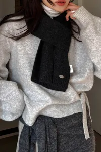 Strickschal Detailaufnahme, einfarbiger weicher warmer Winterschal mit Metalletikett und Pullover.
