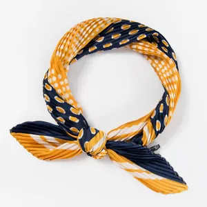 Pleated scarf detail showcasing yellow and navy blue polka dot pattern and neat fabric texture.