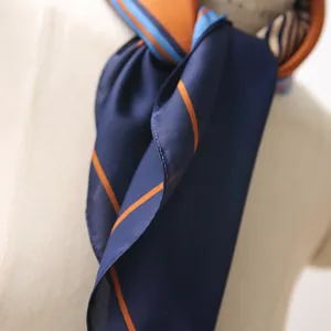 Detail view of navy blue satin silk scarf with orange and blue stripes, elegant neckwear.