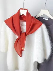 Detailed view of the orange chiffon scarf styled on a white fuzzy sweater for chic elegance.