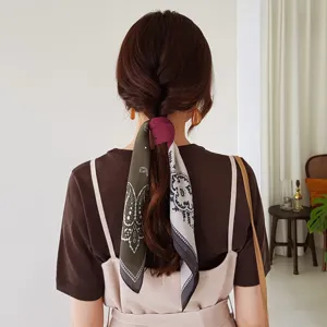 Gedetailleerd overzicht van een paisley zijden sjaal gedragen als haaraccessoire.