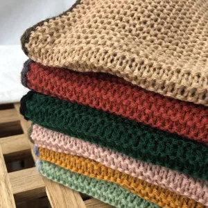 Primer plano detallado de suaves bufandas de punto apiladas en varios colores sólidos.