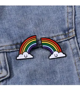 Close-up detail shot of cute enamel pins featuring smiling clouds and colorful rainbow design.