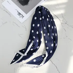 Close-up of pleated navy blue neck scarf with white polka dots and elegant contrast border.