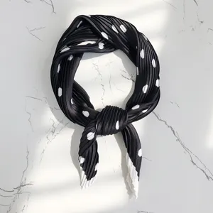 Close-up of pleated black and white polka dot scarf, stylish imitation silk neckerchief detail.