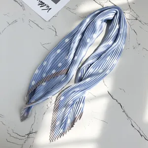 Detailed shot of a blue pleated polka dot silk scarf, showing delicate texture and white dots.