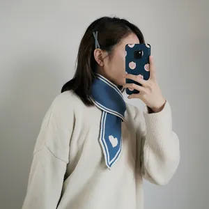 Nahaufnahme des stilvollen blauen Strickhalstuchs mit einem niedlichen weissen Herzmuster.