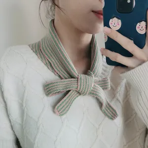 Detailed view of a stylish knitted striped neck warmer scarf in pink and green, cozy winter wear.