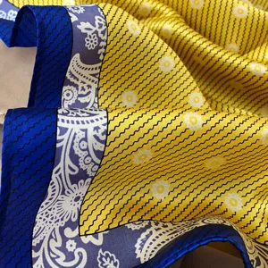 Vista detallada de pañuelo de seda de lujo con textura fina, patrón amarillo vibrante y borde floral.