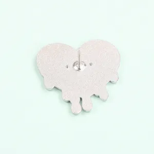 Close-up view of the back side of a silver heart metal brooch pin with secure fastener pin.