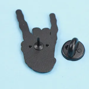 Detailed view of the rock hand gesture metal brooch back with secure rubber clutch pin.