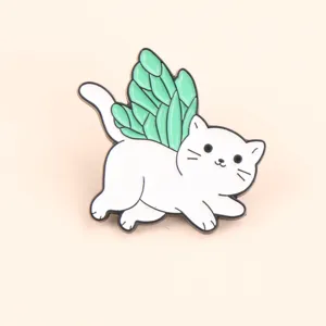 Primo piano dettagliato della graziosa spilla in metallo gatto bianco con ali di farfalla verdi.