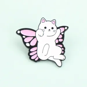 Primo piano della graziosa spilla in metallo smaltato con gatto bianco e ali di farfalla.