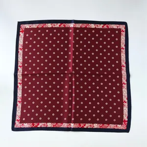 Primer plano detallado de pañuelo de seda burdeos con flores y clásico borde de cachemir.