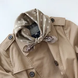 Elegante pañuelo de seda combinado con una gabardina beige clásica para otoño e invierno.