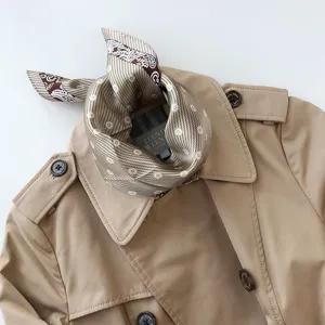 Primer plano de un pañuelo de seda elegante atado alrededor del cuello de una gabardina.