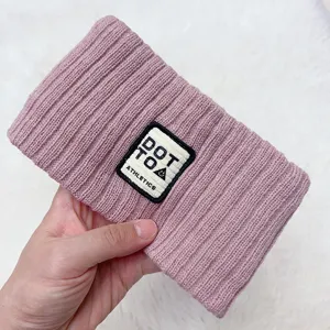 Pink knitted hairband with woven patch label, cozy winter hair accessory for daily wear.