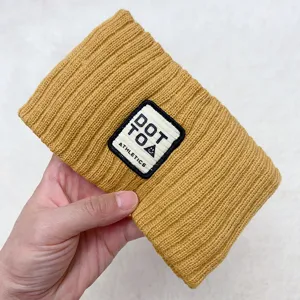 Detailed closeup of the yellow knitted hair band showcasing textured fabric and embroidered patch.