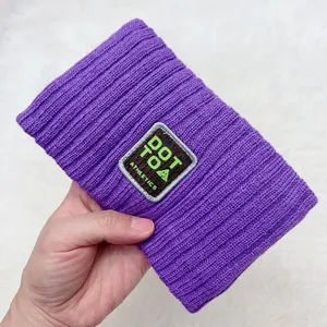 Close-up detail of a purple knitted hair band with embroidered patch letter design, cozy texture.