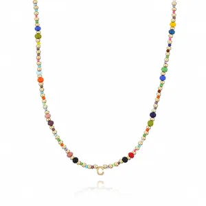 Close-up detail of colorful seed bead necklace featuring golden beads and letter C pendant.