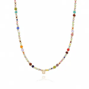 Detail shot of a bohemian colorful beaded necklace with a gold letter pendant and small beads.