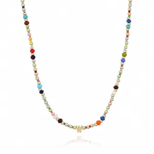 Detailed view of bohemian colorful seed bead necklace with gold metal beads and letter W pendant.