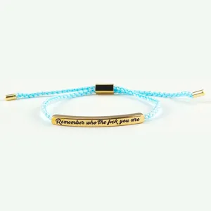 Primo piano dettagliato della barra dorata incisa sul bracciale intrecciato azzurro.