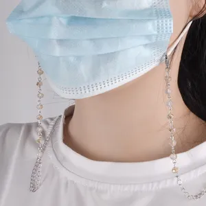 Dettaglio in primo piano della catena per maschera di perle di cristallo e cinturino per occhiali.