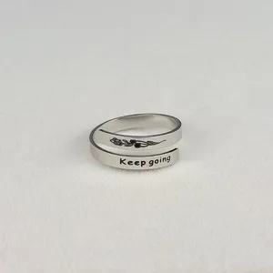 Primo piano dettagliato di anello in acciaio inossidabile con rosa incisa e testo motivazionale.