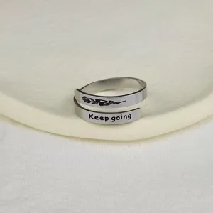 Anello regolabile in acciaio inossidabile con incisione Keep going e dettaglio floreale.