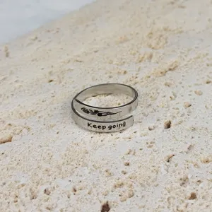 Primo piano di un anello aperto regolabile in acciaio inossidabile con incisione.
