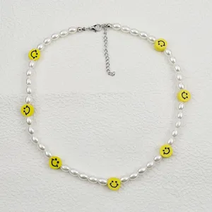 Dettaglio in primo piano della collana di perle bianche con perline smiley gialle e catena.