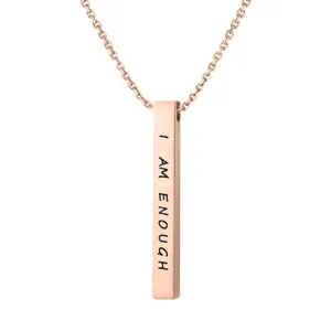 Primo piano di una collana con ciondolo a barra verticale in oro rosa con testo inciso I AM ENOUGH.