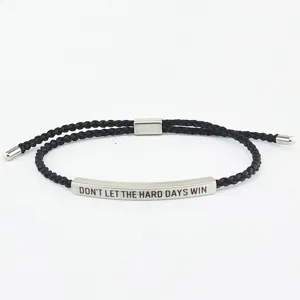 Primo piano di un bracciale in corda intrecciata nera con barra metallica in titanio.