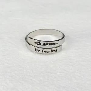 Primo piano di anello aperto in metallo argentato regolabile con incisione e fiore.