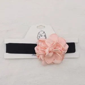 Primo piano dettagliato della collana girocollo in tessuto nero con un fiore di camelia.
