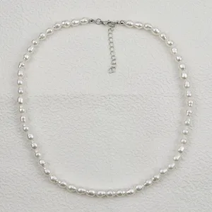 Collana di perle bianche con catenella di estensione in metallo, dettaglio gioiello elegante.