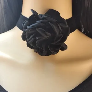 Primo piano dettagliato di una collana girocollo vintage in tessuto nero con fiore di camelia.