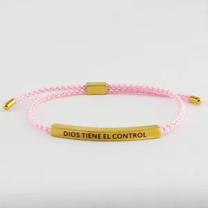 Primo piano del bracciale in corda intrecciata rosa con tubo in metallo dorato inciso.