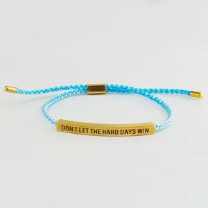 Primo piano dettagliato del bracciale in corda intrecciata azzurra con barra dorata.