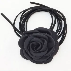 Dettaglio della collana girocollo con fiore di camelia in tessuto nero e lunghi lacci scamosciati.