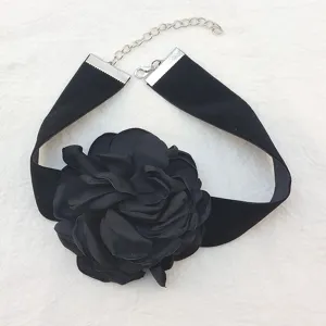 Dettaglio in primo piano della collana choker elegante in tessuto nero con fiore di camelia.