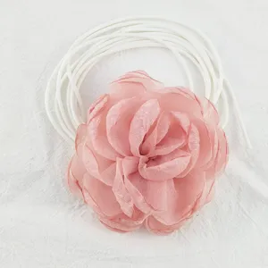 Dettaglio in primo piano del cinturino choker con fiore in tessuto rosa, texture petali.