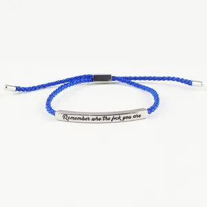 Dettaglio del bracciale in corda intrecciata con targhetta in metallo inciso e chiusura regolabile.
