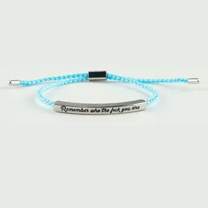 Primo piano del braccialetto regolabile intrecciato azzurro con barra metallica incisa.