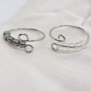 Anello antiansia in acciaio inossidabile con perline di vetro, dettaglio del design rotante.
