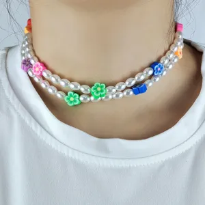 Gros plan détaillé d'un collier ras du cou en fausses perles avec des fleurs en argile.